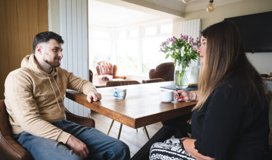 Shon and his mum sat at a kitchen table